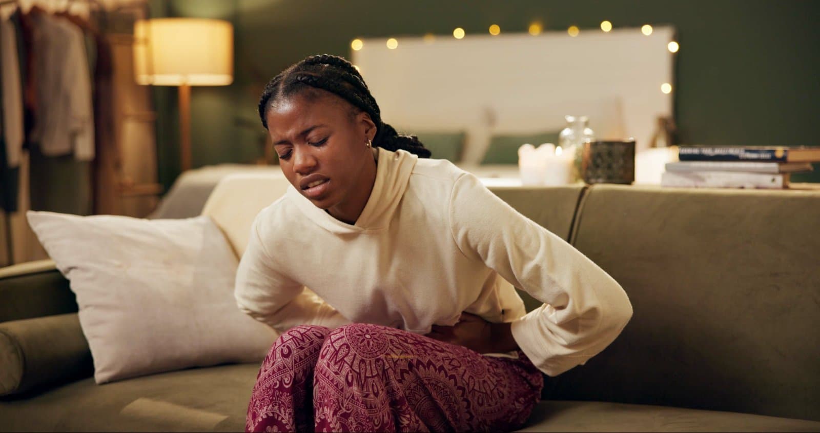 A woman resting on a sofa with a hot water bottle, managing cramps